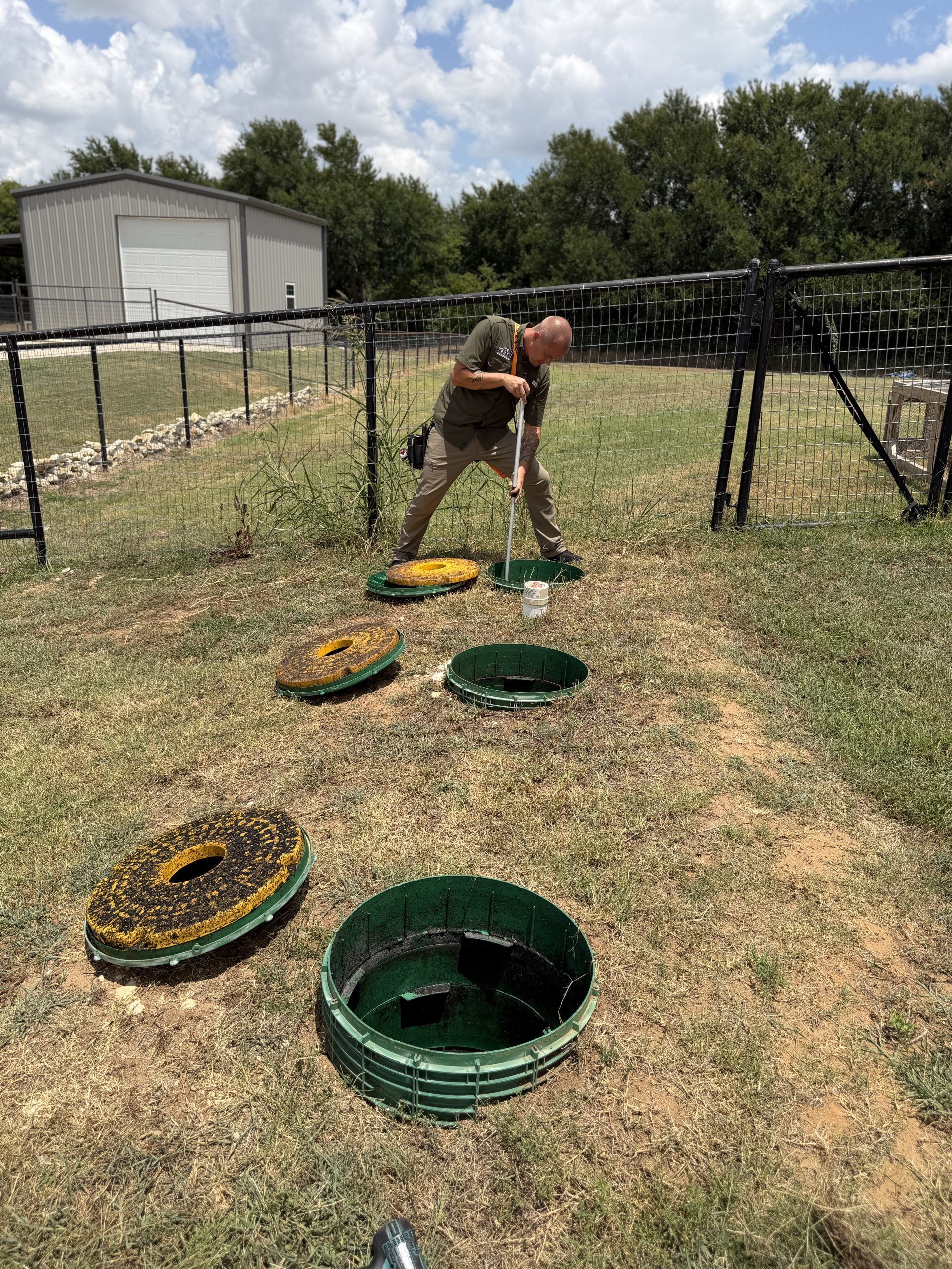 Inspector evaluating septic system tanks and lids during septic inspection in Midlothian TX